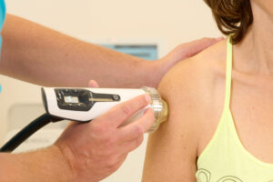 Dr. Messenbäck wendet die Stoßwellentherapie beim der Schulter einer Patientin an